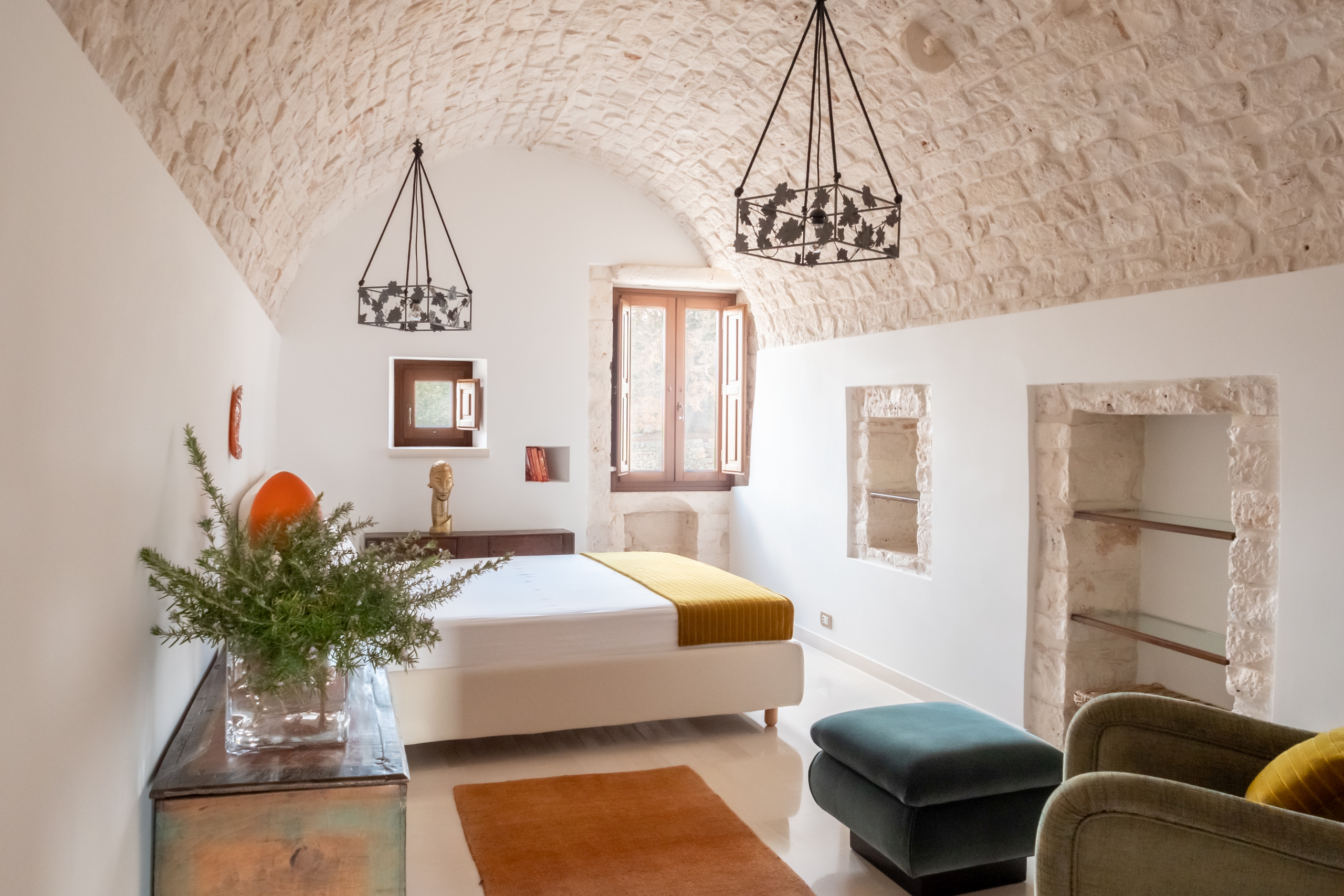 Airy and cosy, a bedroom that keeps an ancient machicolation still intact.